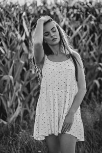 Portrait of young woman standing against plants