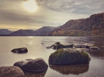 Scenic view of rocks in lake against sky during sunset