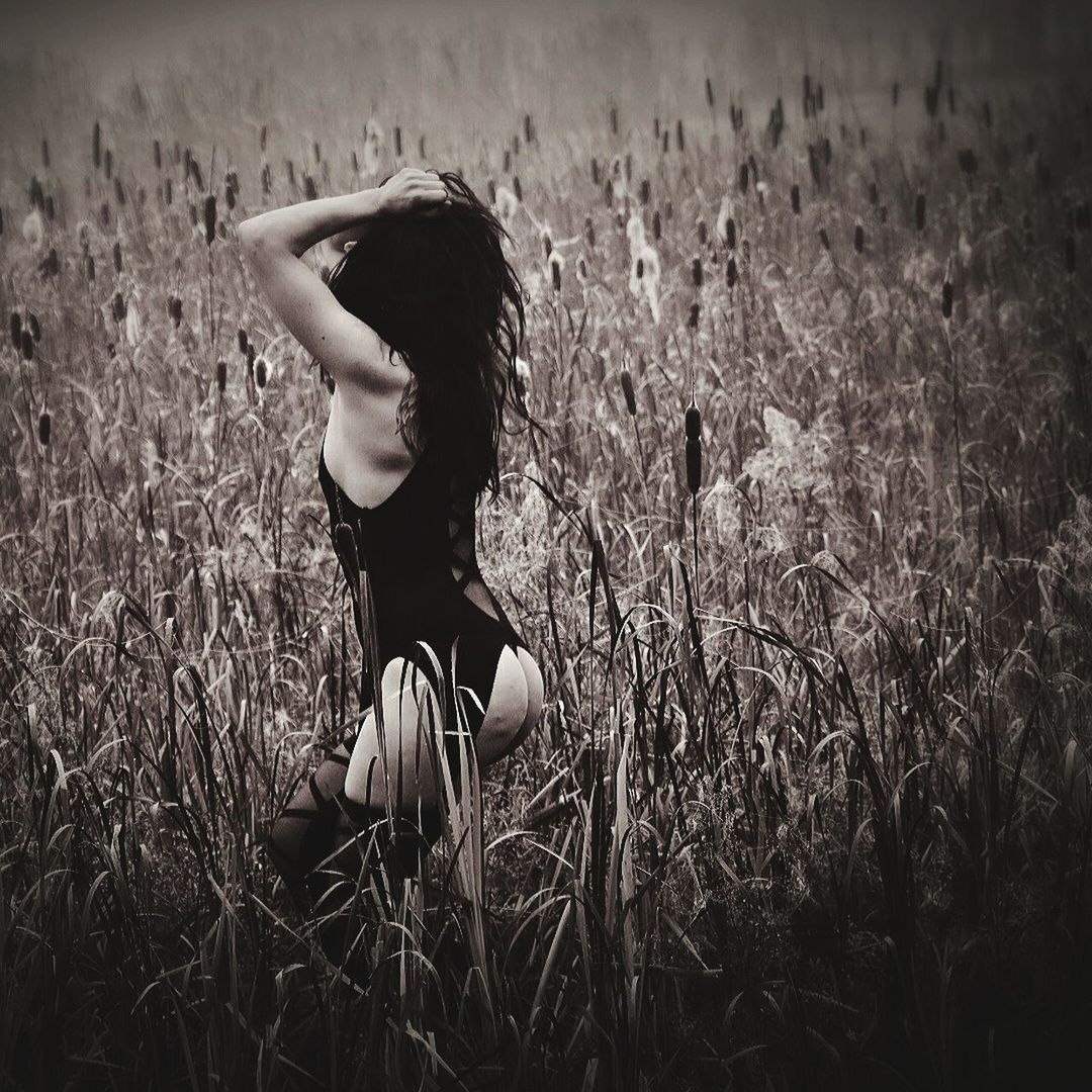 YOUNG WOMAN STANDING IN FIELD