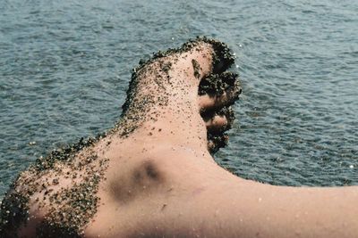 Low section of man covered with sand at beach