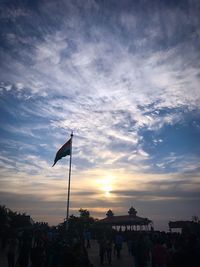 People on street against sky during sunset