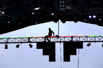 Low angle view of silhouette people on bridge against sky