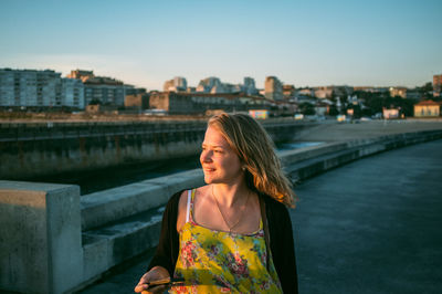 Portrait of woman walking along footpath at sunset