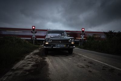 Cars on road against cloudy sky