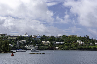 Scenic view of sea by city buildings against sky