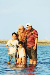 Portrait of happy family in sea against clear sky