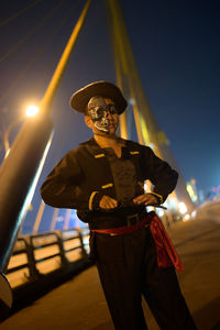 Portrait of young man wearing pirate costume standing on bridge at night