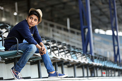 Fashionable teenager sitting on seat at stadium