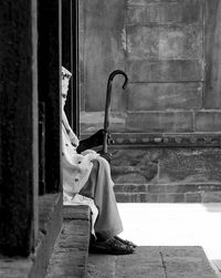 Woman with walking cane sitting amidst columns