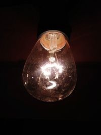 Close-up of illuminated light bulb against black background