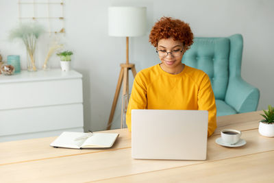 Woman using laptop while sitting on table