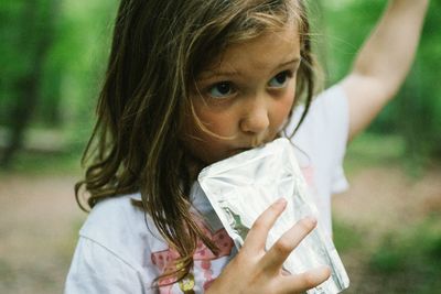 Close-up of girl drinking juice while standing on field