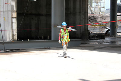 Man carrying pipes on shoulder at construction site on sunny day