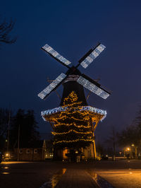 Low angle view of illuminated traditional windmill against sky at night