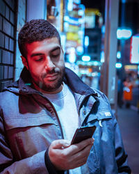Young man using mobile phone on street