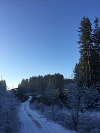 Snow covered landscape against clear blue sky