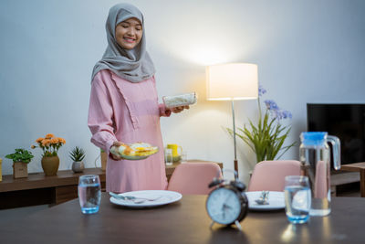 Portrait of woman sitting on table at home