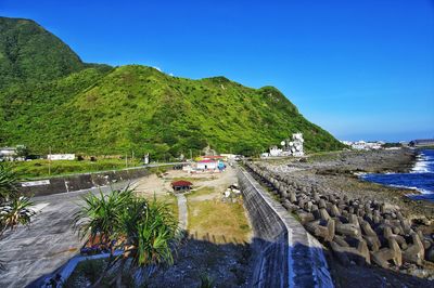 Scenic view of sea and mountains against clear blue sky