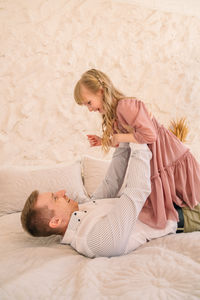 Portrait of smiling mother and daughter lying on bed at home