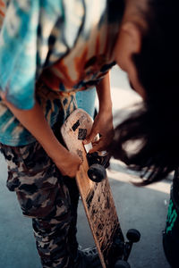 Midsection of man holding skateboard 