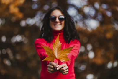 Portrait of smiling woman wearing sunglasses standing outdoors during autumn