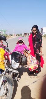 Woman riding motorcycle on street against clear sky