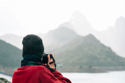 Rear view of man looking at mountains during winter