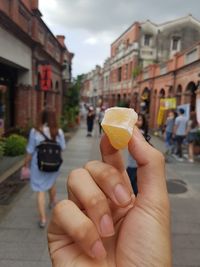 Man holding ice cream on street in city