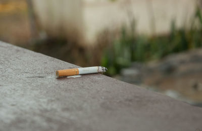 Close-up of cigarette smoking on retaining wall