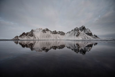 Scenic view of lake by snowcapped mountain against sky