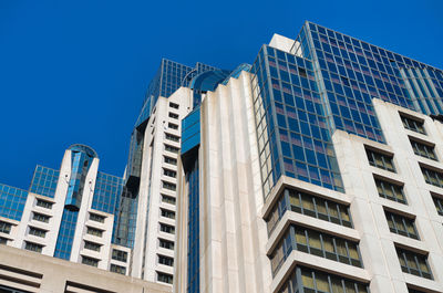 Low angle view of modern buildings against blue sky