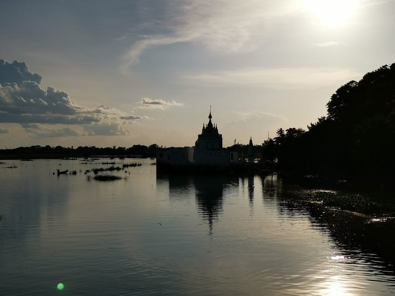 BUILT STRUCTURE BY RIVER AGAINST SKY AT SUNSET