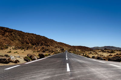 Road leading towards mountain against clear blue sky. el teide, teneriffe,  spain.