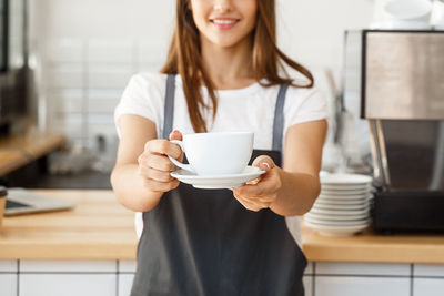 Midsection of barista holding coffee cup