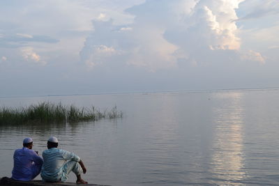 Rear view of people in sea against sky