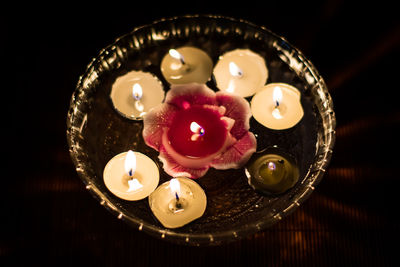 High angle view of tea lights in water filled glass bowl on table