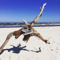 Driftwood on beach against clear sky