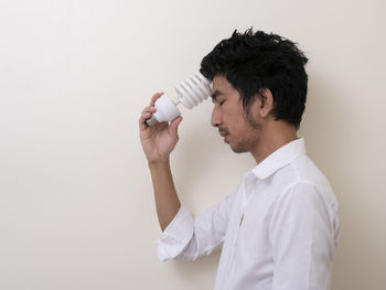 Midsection of man drinking glass against white background