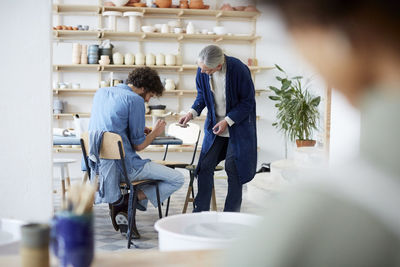 Smiling male and female students learning pottery in art studio