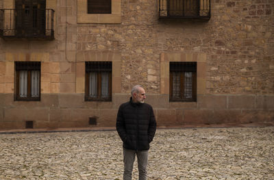 Adult man in winter clothes standing against old building. siguenza, castilla la mancha, spain