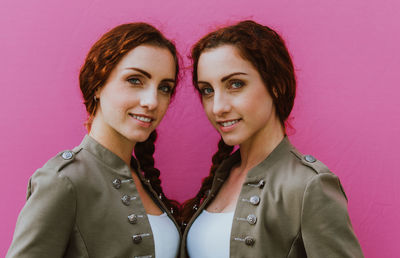 Portrait of smiling siblings against pink background