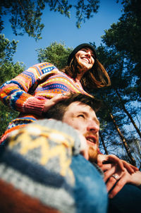 Happy young woman with arms raised against sky