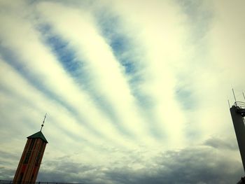 Low angle view of communications tower against cloudy sky