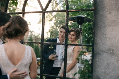 Reflection of newlywed couple on glass window