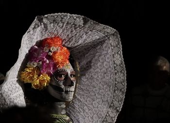 Close-up of man wearing flower against black background