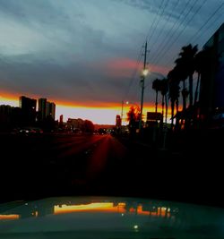 Cars on road against sky during sunset