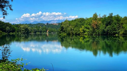 Scenic view of lake by trees against blue sky