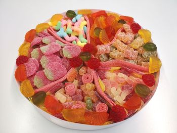 High angle view of multi colored candies in bowl against white background