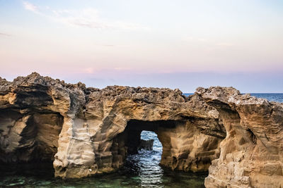 Rock formation in sea against sky