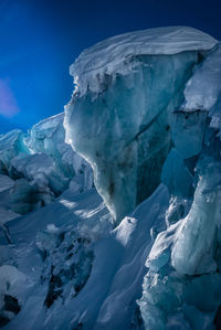 Snow covered landscape against blue sky